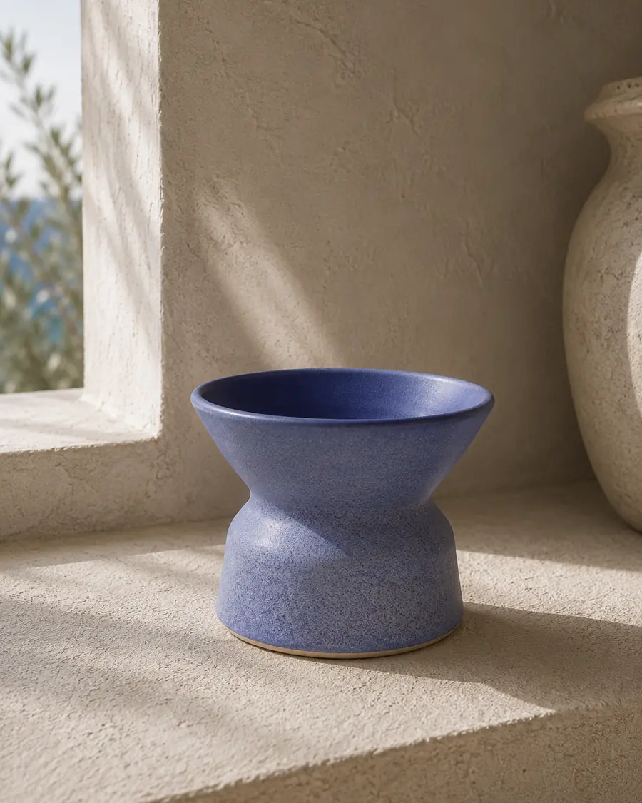 Periwinkle blue sculptural vessel on a stone window sill